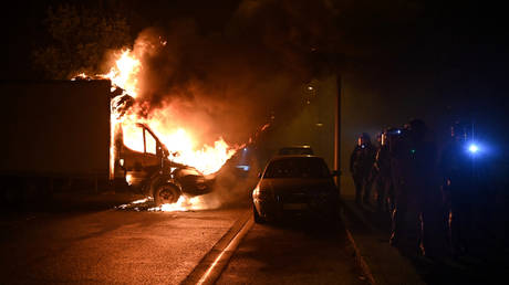 French anti riot police officers walk past a burning truck in Nantes, western France on early July 1, 2023.